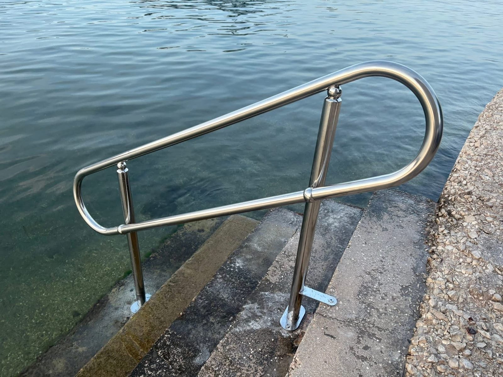 Inox rukohvat postavljen uz betonske stepenice koje ulaze u more.