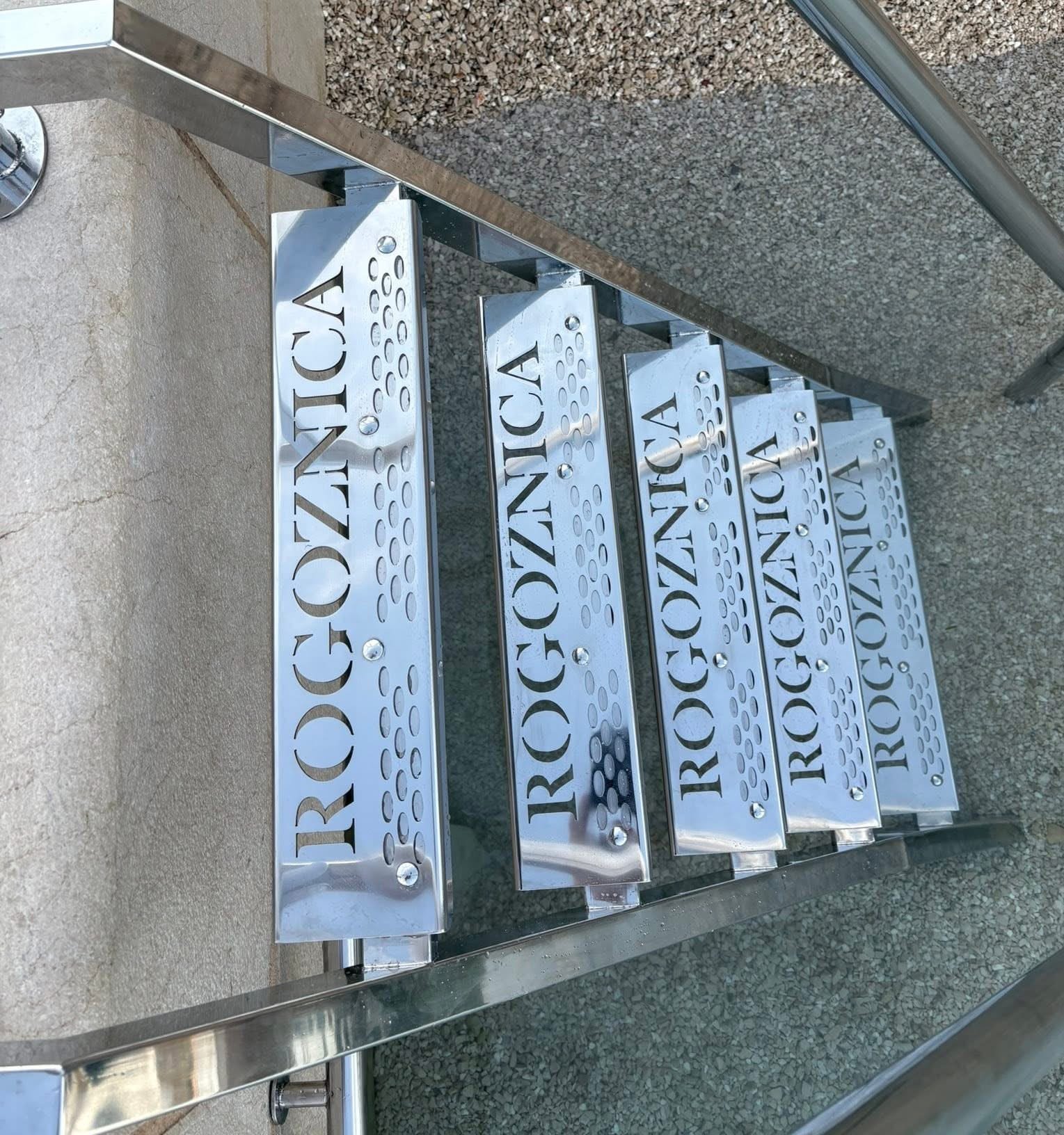 Detalj inox gazišta s laserski izrezanim natpisom i perforacijom te vijčanim spojevima na nosaču.